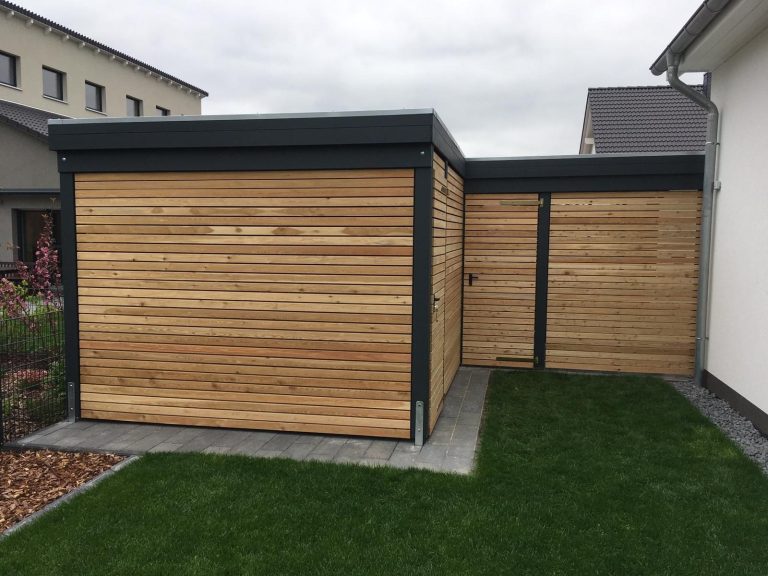Carport mit Geräteraum , Wandverkleidung mit Rhombusleisten aus Douglasie Moderne Gartenhütte mit Holzverkleidung und flachem Dach in einem gepflegten Garten.